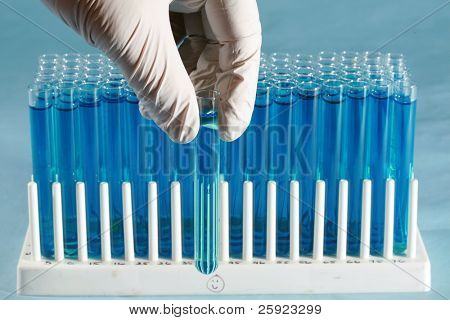 a science or medical research scientist holds and examines a test tube filled with a blue liquid