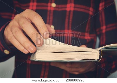 Close Up Of A Young Male In A Chequered Shirt Holding The Book And Turning Over The Page. Ingusitive