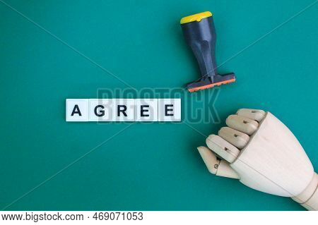 Wooden Hand And Stamp With The Word Agree Alphabet Letters. The Concept Of Mutual Consent. The Conce