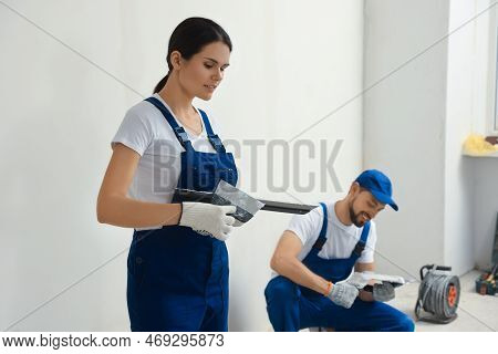 Professional Workers With Putty Knives Near Wall Indoors