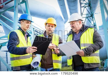 Engineers discussing maintenance of a petrochemical plant. Technical inspection. Oil and gas industry.