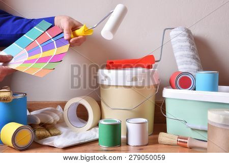 Painting Tools For Home On Parquet With White Wall Background And Painter Choosing Colors On A Color