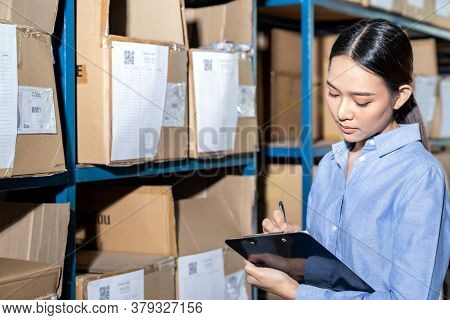 Close up of Asian smart businesswoman working with product inventory in distribution warehouse. For business warehouse inventory and logistic concept.