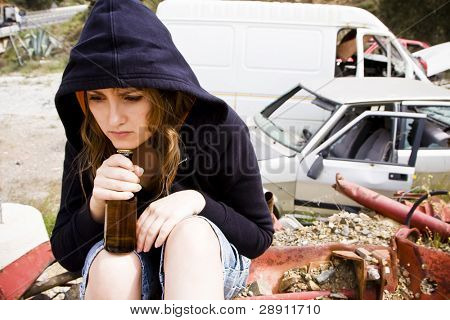 Young woman taking beer in the scrapyard