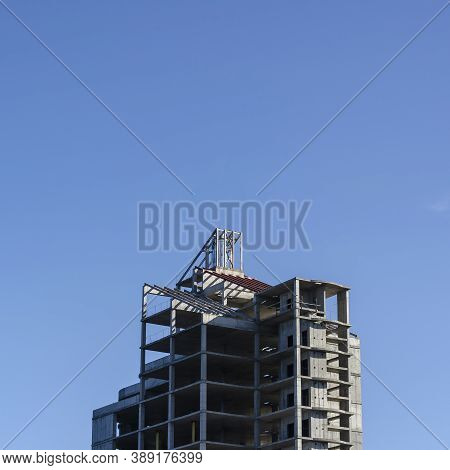 Unfinished Skyscraper Against The Blue Sky. A Concrete Multi-storey Building Of A Modern Business Ce