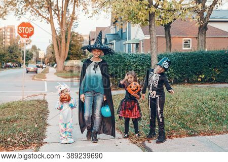 Trick Or Treat. Mother With Children Going To Trick Or Treat On Halloween Holiday. Mom With Kids In 