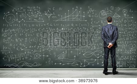 Business person standing against the blackboard with a lot of data written on it