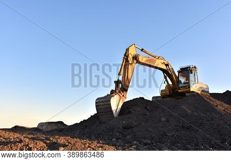 Excavator Working On Earthmoving At Open Pit Mining. Yellow Backhoe Digs Sand And Gravel In Quarry. 