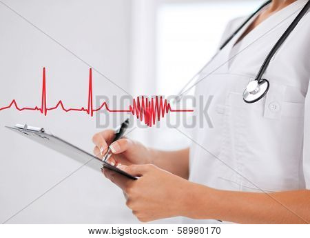 healthcare and medical concept - female doctor with stethoscope writing prescription