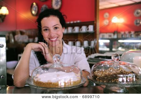 Proprietário de uma loja de café mostrando seus bolos saborosos