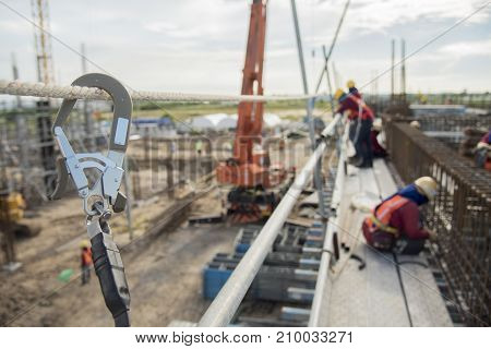 Working at height equipment. Fall arrestor device for worker with hooks for safety body harness on selective focus. Worker as a background.