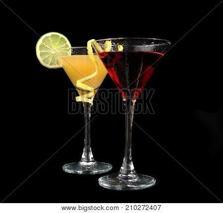 Two cocktails cosmopolitan cocktails decorated with citrus lemon twist yellow and red martini drink with strawberry isolated on a black background