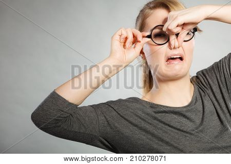 Bad smell concept. Young woman feels disgust pinches her nose with fingers because of odor stench unpleasant stink. Facial reaction.