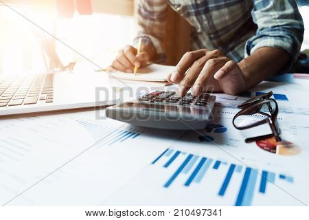 Close Up Of Businessman Or Accountant Hand Holding Pen Working On Calculator And Laptop Computer To