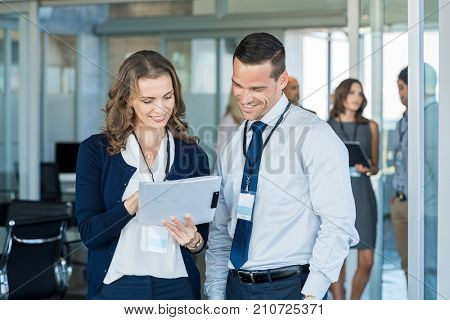 Company employees reading report file at business annual meeting. Manager and smiling businesswoman working together in modern office. Happy businessman and business woman discussing report.