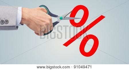 business, people, financial crisis, sale and default concept - close up of businessman hand with scissors cutting percents over gray background