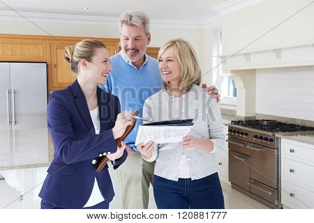 Female Realtor Showing Mature Couple Around House For Sale