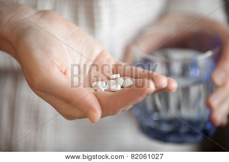 Womans Hands Holding Heap Of White Round Pills And Glass Of Water