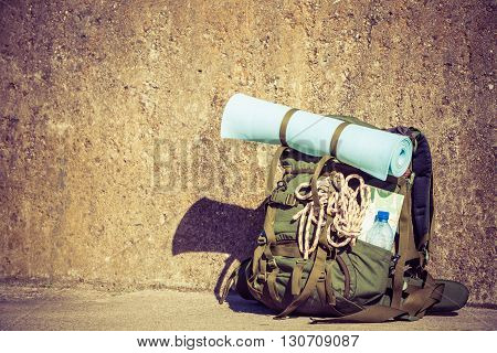 Hiking backpack camping and mountain exploring tourist equipment outdoor on grunge wall. Adventure summer tourism active lifestyle