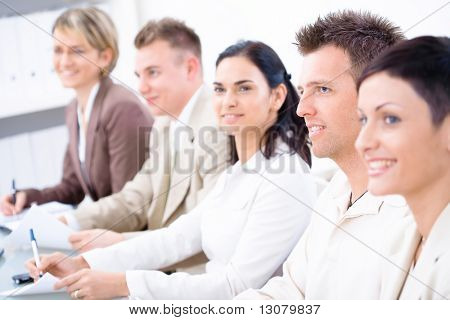 Five business people sitting in a row and writing notes on a business training. Selective focus placed on businessman in front. Browse my portfolio for vertical version.