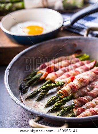 Asparagus. Asparagus and roll bacon. Grilled asparagus with rolled bacon and fried egg. Fried old pan full of rolled bacon with green asparagus and fried egg.