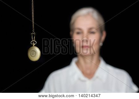 Woman being hypnotized with pendulum against black background