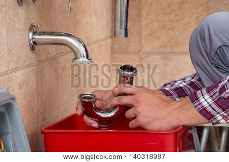 Close-up Of Plumber's Hand Fixing Sink In Bathroom