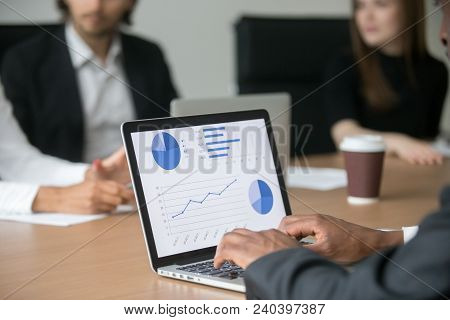 Black Project Manager Working On Computer Analyzing Statistics On Screen At Multiracial Meeting, Afr