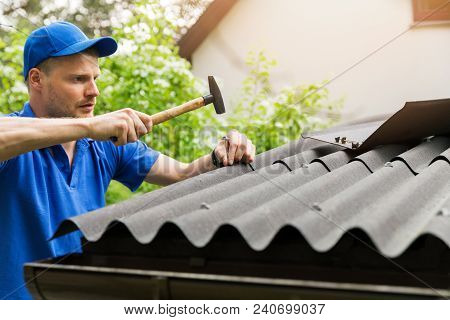 Roofer In Blue Uniform Installing Bitumen Roof Sheets