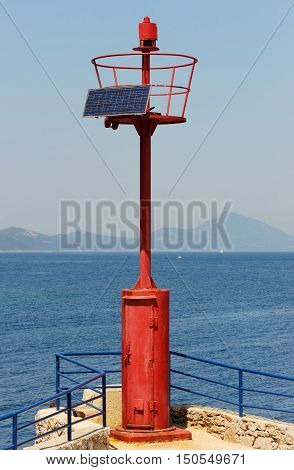 Mediterranean beacon with solar cells and coastline in the background