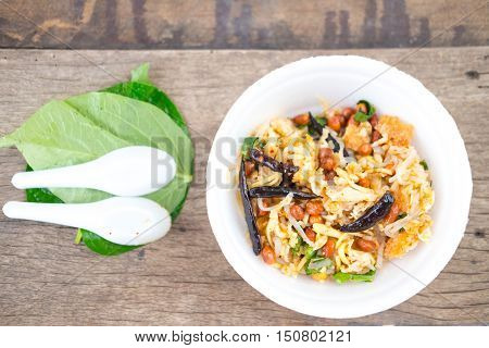 Thai Food (Yam Naem Khao Thot) Recipe Spicy Salad of Curried Rice Croquettes Fermented Pork Ginger and Peanuts in wite plate on wood plate