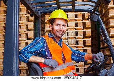 Handsome Smiling Worker Driving Forklift In Warehouse. Woodworking Industry Concept.