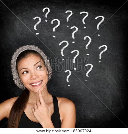 Student thinking with question marks on blackboard. Asian female young adult university or college student looking up at written drawings of question marks on chalkboard wondering career choices.