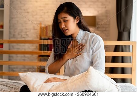 Portrait Of 20s Young Asian Woman Having Difficulty Breathing In Bedroom At Night. Shortness Of Brea