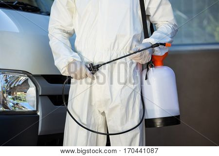 Mid section of pest control man standing next to a van on a street