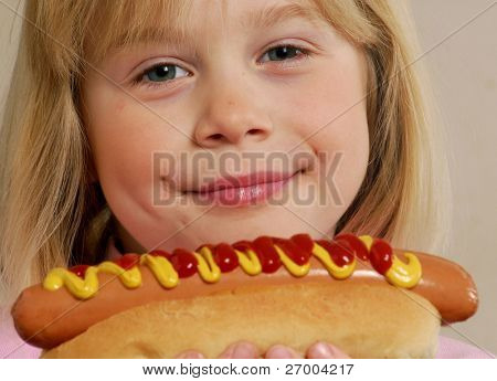 Little girl eating a hot dog.Kid eating hot dog.