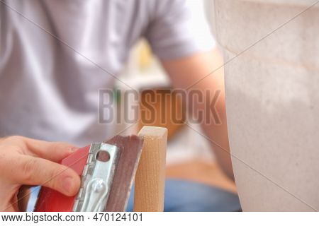 A Man Grinds Wood With Sandpaper. The Process Of Grinding A Piece Of Wood With A Bar With Sandpaper.