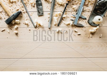 High angle view of shabby woodworking tools lying on wooden table, shavings scattered everywhere