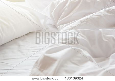 wrinkle messy blanket and white pillow in bedroom after waking up in the morning from sleeping in a long night details of duvet and blanket an unmade bed in hotel bedroom with white blanket.