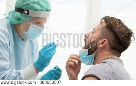 Doctor in a protective suit taking a throat and nasal swab from a patient to test for possible coronavirus infection