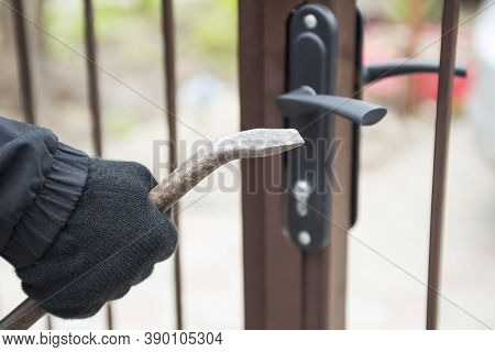 Burglar Trying To Break The Gate With A Crowbar. Burglar Trying To Force A Lock Using A Crowbar.