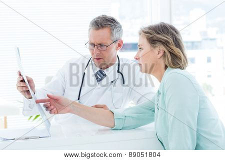 Doctor having conversation with his patient and holding xray in medical office