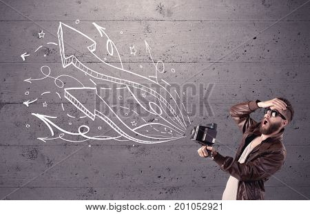 A hipster guy opening his point of view through looking a vintage camera concept with illustratied drawn arrows on urban wall