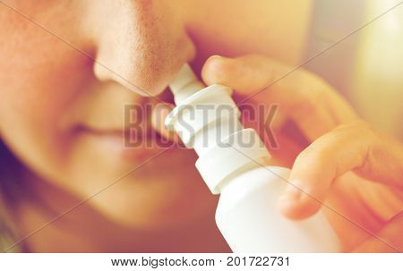 healthcare, flu, rhinitis, medicine and people concept - close up of sick woman using nasal spray