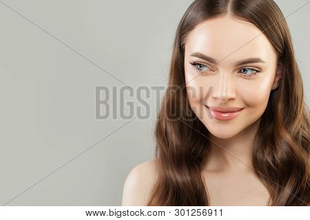 Portrait Of Cheerful Woman With Clear Skin And Healthy Curly Hair On Gray Background. Beautiful Face