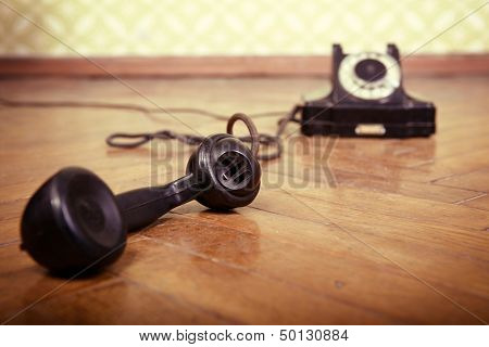 vintage old telephone, black retro phone is on the floor of used parquet, toned