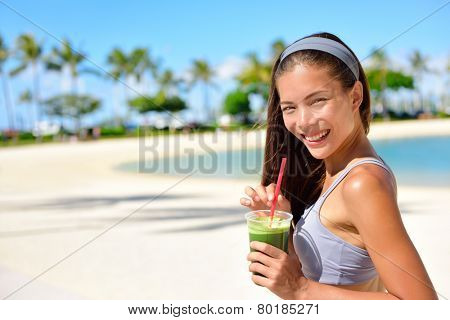 Green detox smoothie - woman drinking vegetable smoothie after fitness running workout on summer day. Fitness and healthy lifestyle concept with beautiful fit mixed race Asian Caucasian model.