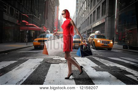 ragazza alla moda con borse della spesa attraversando una strada di città