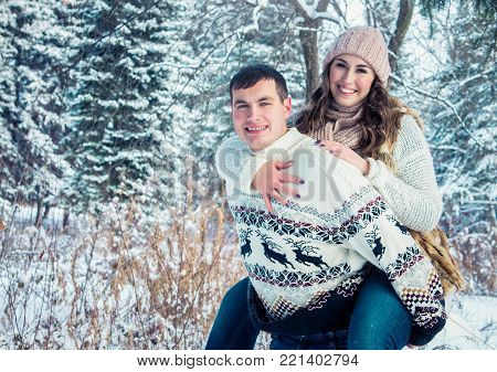 Woman rides on her boyfriend's back in winter forest