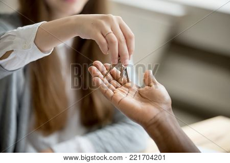 African american black man buyer getting keys to new home from woman realtor, buying rental sale house and real estate purchase ownership concept, mortgage loan investment, close up view of hands